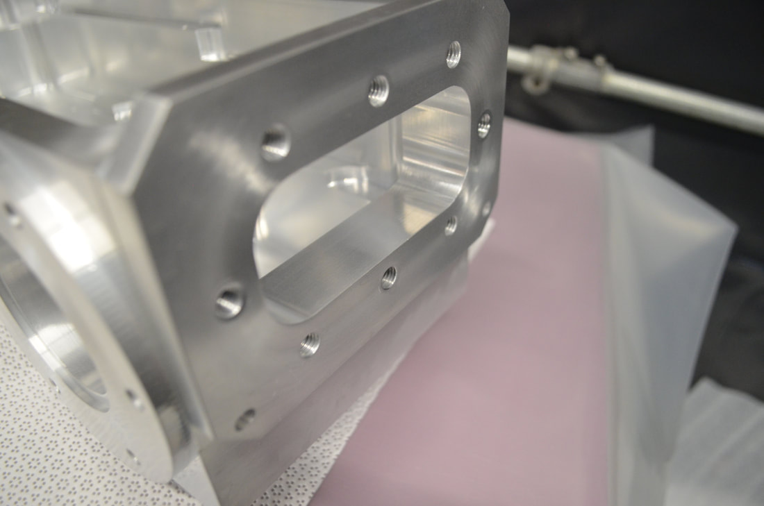 Rectangular port on a vacuum chamber machined out of a solid block of aluminum. The perpendicularity between the polished mounting face and the internal surfaces was a critical dimension.