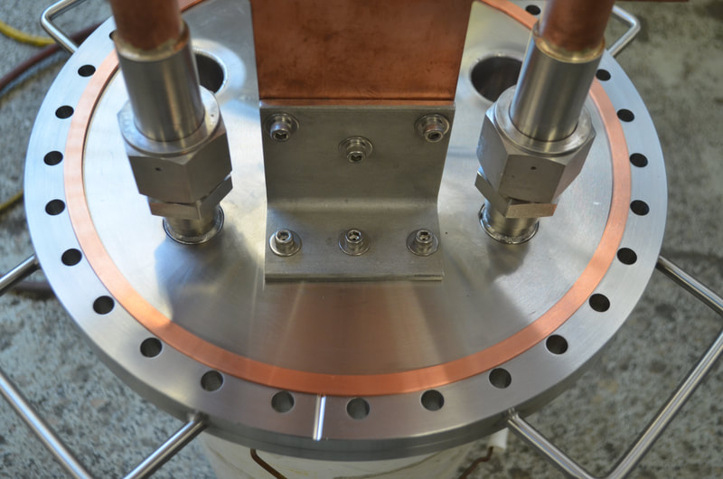 Custom vacuum chambers often require special covers with unique features like this copper heat sink and liquid cryogen feed throughs. 