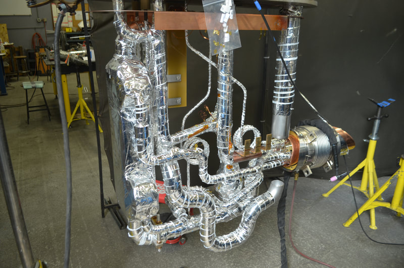 Fabrication of cryogenic distribution can for an accelerator cryomodule cryogen distribution system. The piping shown being build from a 'top plate' fixture with heat exchanger, check valve, control valve, and relief piping all multilayer insulation wrapped. 